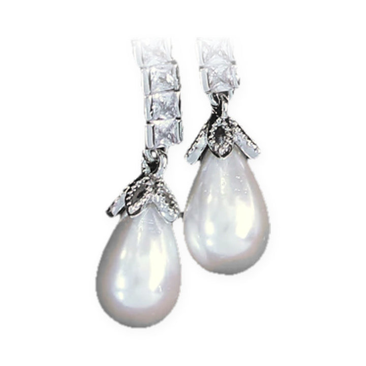 Close-up of the faux pearl teardrops under silver-tone leaf caps beneath square cubic zirconia links